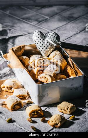 Shortcrust pastry cookies with pistachio filling, pistachio rolls on gray tiles, high contrast, vertical Stock Photo
