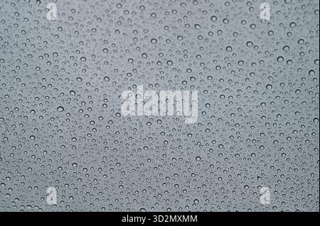 Water droplets forming patterns on window glass during rain Stock Photo