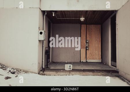 Abandoned apartment entrance with boarded door and worn concrete Stock Photo