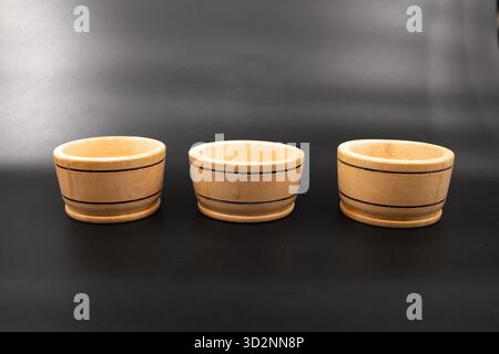 Three small wooden bowls on dark background for minimalistic kitchen design Stock Photo