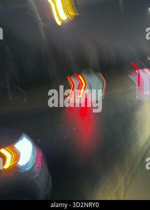 Long exposure of cars driving in the rain at night, creating colorful light trails on wet roads in Edmonton, Alberta, Canada Stock Photo