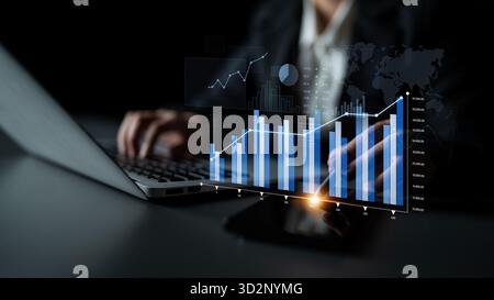 Business professional analyzing financial data using modern technology and digital graphs on a laptop screen in a dark environment for market insights Stock Photo