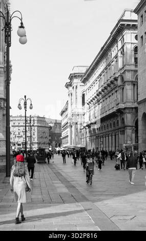 Young woman in a red beret walking through a busy street near the Galleria Vittorio Emanuele II in Milan, Italy, Stock Photo