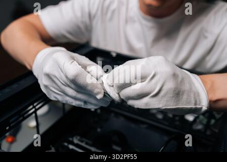 Close-up hands of technician male cleaning computer processor with white cloth, preparing for installation in computer case, ensuring optimal Stock Photo