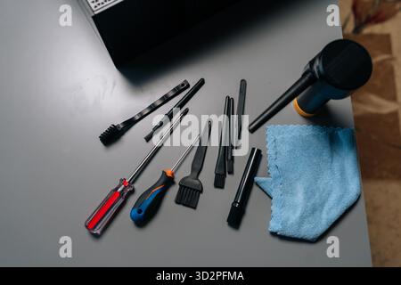 Top view of computer maintenance professional cleaning desktop case, using precision tools on gray surface, preventing hardware dust buildup Stock Photo