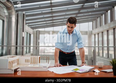 Young businessman, engineer working in office, working on plan or technical document. Stock Photo