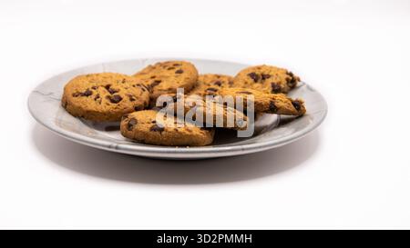 Freshly baked chocolate chip cookies arranged on a plate against a clean white background. Sweet dessert or snack concept. Stock Photo