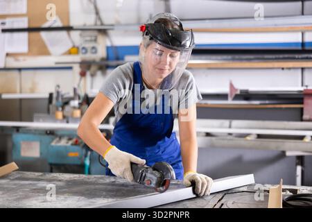 Workwoman cutting plastic profile with angle grinder in workshop Stock Photo