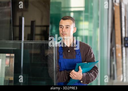 Worker inspecting glass panels and recording check results Stock Photo
