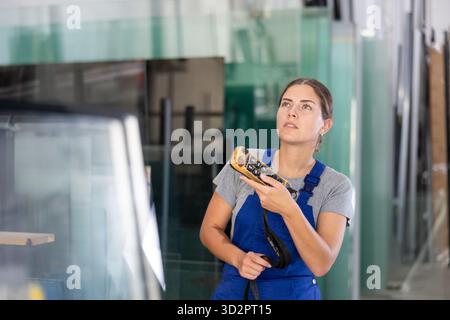 Female worker using remote control to operate machinery in glass workshop Stock Photo