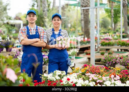 Two friendly employees man and girl garden center, are waiting for visitors. Stock Photo