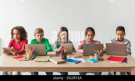 Five School Kids Participating in Online Class Using Laptops in a Modern Classroom Setting Stock Photo