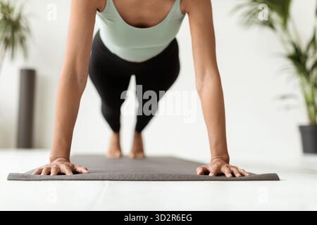 Young Woman Exercises Indoors With Push Ups on Fitness Mat in a Modern Studio Stock Photo