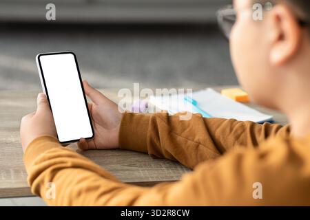 Chubby Boy Using Smartphone During Homework in Cozy Home Setting Stock Photo