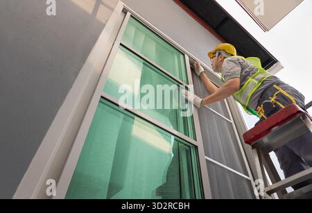 Construction worker repairing the sliding window. Open cap of adjust rail wheel. Stock Photo
