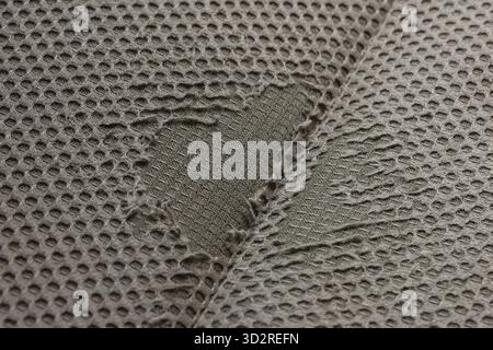 Close up of gray mesh fabric with large tear. hole in material broken heart shape. texture background showing damage and heartbreak from wear and tear Stock Photo