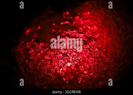 Mysterious glowing red crystal cluster on dark background. vibrant, abstract texture showing macro view of mineral shining with intense energy and lig Stock Photo