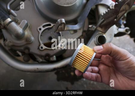 Close up of mechanic hand doing motorcycle engine maintenance. Focused repair and service work, changing dirty oil filter part for engine performance Stock Photo