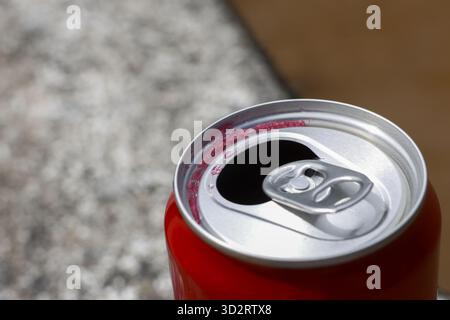 Close up macro view of an open red aluminum beverage can with metal pull tab. refreshing soda drink container sits empty, piece of recyclable waste af Stock Photo