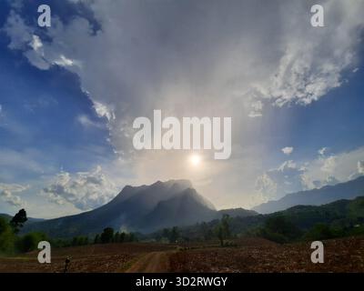 Dramatic sky over majestic mountain peak at sunrise brings sense of awe and tranquility, with sunrays breaking through clouds creating breathtaking na Stock Photo