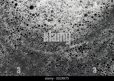 Close up of white and gray foam bubbles, creating an intricate texture and abstract pattern on liquid surface. Varying sizes of delicate suds convey r Stock Photo