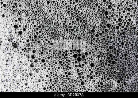 White foam and numerous bubbles create an intriguing, abstract texture. Soapy washing on surface provides macro view of this clean environment, evokin Stock Photo