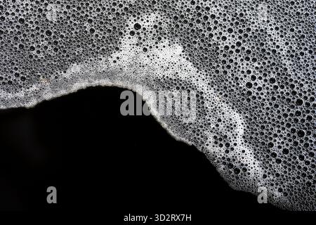 White foam and small bubbles create an abstract, clean surface. Fresh liquid suds flow gently, presenting light, airy texture, evoking feeling of tran Stock Photo