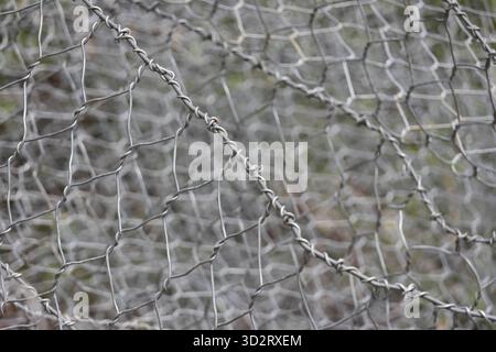 Wire mesh metal fence forms protective pattern, texture, gray silver, strong Stock Photo
