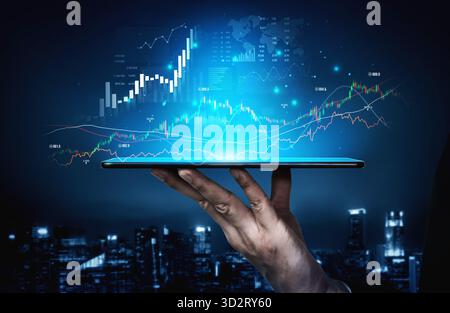 A hand holds a tablet displaying dynamic digital charts and graphs against a city backdrop, representing the future of business and financial analysis Stock Photo