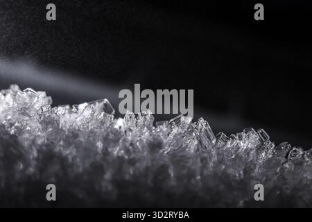 Beautiful abstract macro closeup of frozen ice crystal pattern. cold, white, natural texture of water formations creates stark contrast against black Stock Photo