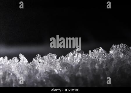 Stark macro detail of cold ice crystal structure on black background. This frozen winter texture shows an abstract, clear, sharp pattern with chilling Stock Photo