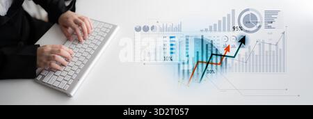 A businessman uses a keyboard to analyze financial data on a computer. The image features graphs and charts illustrating growth trends and performance Stock Photo