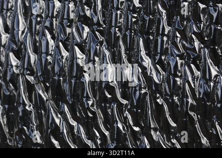 Abstract view of wrinkled and reflective heat protection sheet. This metallic insulation foil creates an industrial texture and dark, shiny background Stock Photo