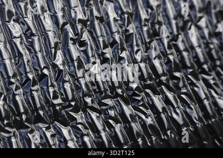 Abstract background of silver heat protection sheet with crinkled texture. shiny, metallic foil insulation creates modern, industrial pattern with lig Stock Photo
