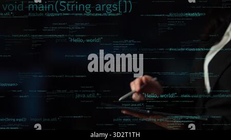 A close-up of hands holding a tablet with dynamic computer code displayed on the screen. This abstract image represents modern technology and software Stock Photo