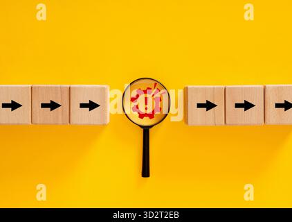 Magnifying glass is focusing on red warning sign inside gear on yellow background, representing troubleshooting and problem solving Stock Photo