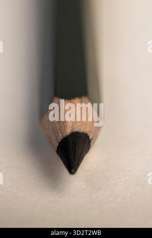 a black wooden pencil folded on cheap loose paper, one wooden pencil with graphite lead for drawing or other work Stock Photo