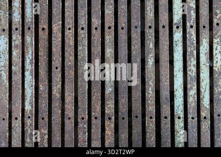 Vertical rustic brown metal fence pattern for background. An aged weathered abstract industrial surface texture with distressed grunge design showing Stock Photo