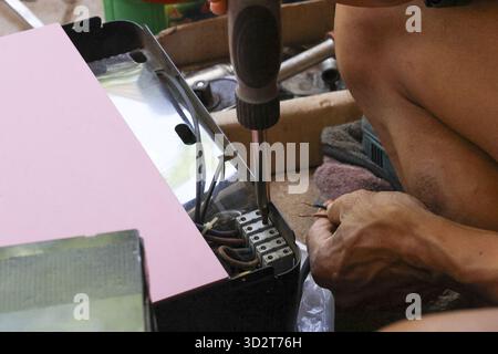 Close up of man hand using screwdriver for electronic repair. Focused person fixing broken equipment, device showing skill, handiwork and maintenance Stock Photo