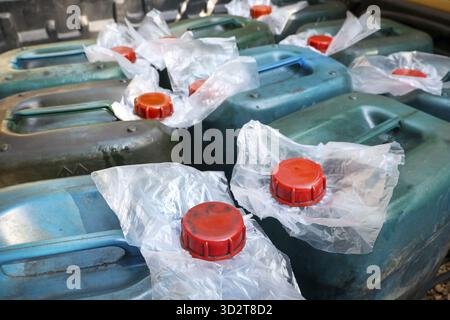 Close up view of many old blue plastic jerrycans with red caps for storing liquid. collection of dirty canisters represents concept of shortage, stora Stock Photo