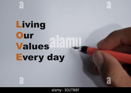 Concept of LOVE - Living Our Values Every day write on book isolated on Wooden Table. Stock Photo