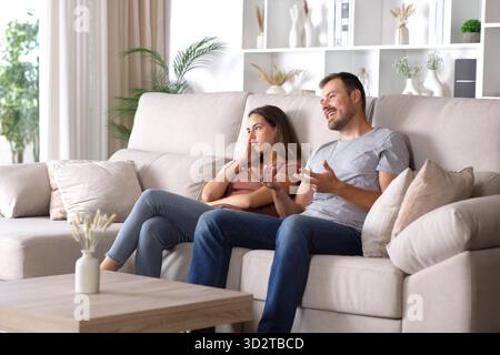 Bored woman listening her partner sitting on a couch at home Stock Photo
