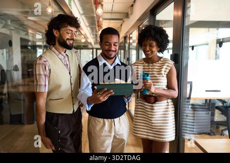 Diverse business colleagues collaborating on tablet in office Stock Photo