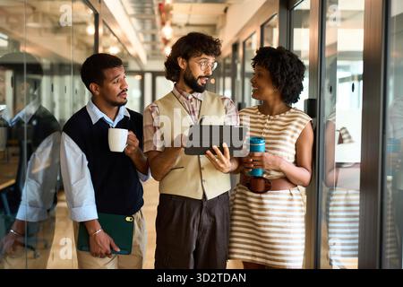 Coworkers discussing project using digital tablet in office hallway Stock Photo