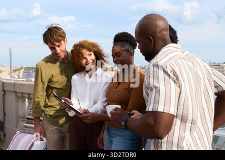 Diverse team meeting outdoors discussing project on tablet Stock Photo