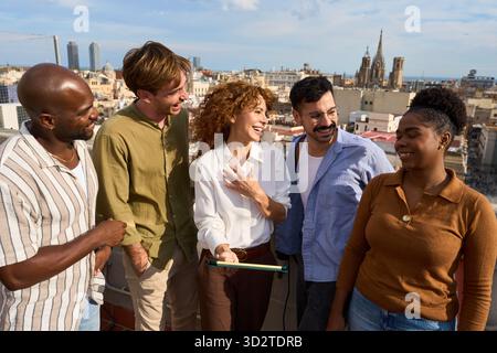 Diverse friends laughing together on barcelona rooftop Stock Photo