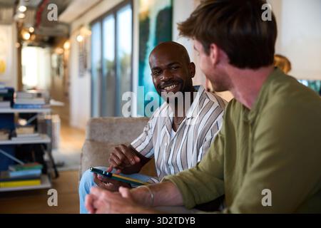 Diverse men friends sharing a laugh using technology Stock Photo