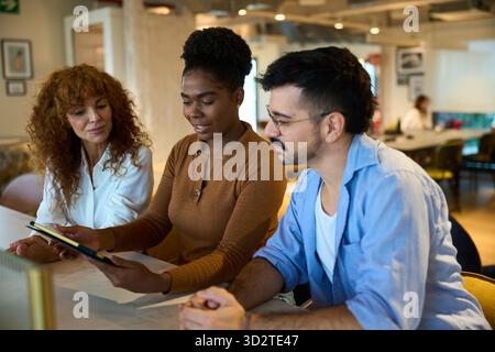 Diverse business team collaborating on tablet in office Stock Photo