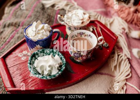 Vintage teacups and cream on red tray with pink fabric background Stock Photo