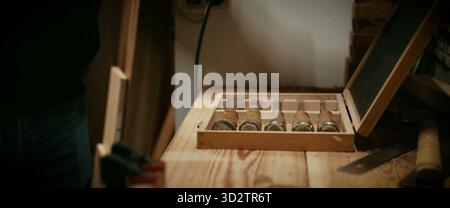 A craftsman's woodworking chisels displayed in a box on a wooden bench Stock Photo